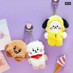 three small stuffed animals hanging from key chains on a purple surface next to a card and ice cream cone