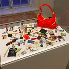 a red purse sitting on top of a white table covered in lots of different items