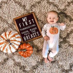 a baby is laying on the floor next to some pumpkins and a sign that says, my first thanksgiving mama please