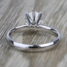 a close up view of a diamond ring on a wooden surface