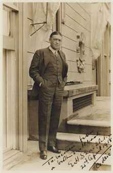 an old black and white photo of a man standing in front of a door with his hands in his pockets