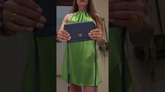 a woman in a green dress is holding a blue folder and looking at the camera