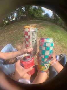 two people sitting on the ground with cans in their hands