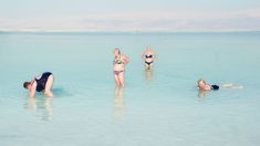 three people are in the water and one person is on their stomach, while two others are swimming