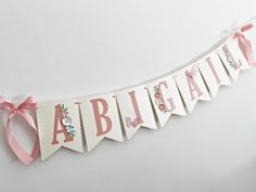 a pink and white banner with the word abigail hanging from it's side