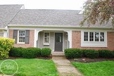 a small brick house with green grass and bushes