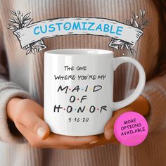 a person holding a white coffee mug with the words, customizable where you're my maid of honor