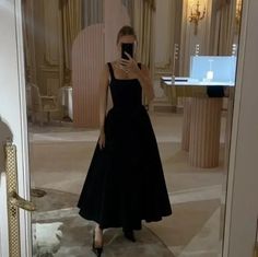 a woman in a black dress taking a selfie