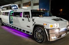 a white hummer limo parked in front of a building with purple lights on it