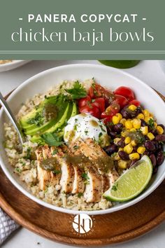 a white bowl filled with chicken, rice and veggies on top of a wooden plate