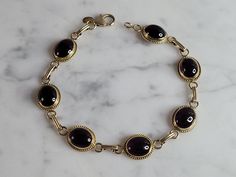 "A WOMENS VINTAGE ESTATE 14K GOLD AMETHYST BRACELET.  BRACELET IS 7 3/4\" LONG BY 3/8\" WIDE, AND WEIGHS 9.8g.    BRACELET IS MARKED \"CARLA, 14KT\".    STONES ARE A LITTLE DECEIVING DEPENDING ON THE LIGHT.  LOOKS LIKE A DARK RED COLOR IN CERTAIN LIGHT.   NOT SURE IF THE STONES ARE REAL OR MAN MADE.  THIS WOULD MAKE A LOVELY GIFT FOR THAT SOMEONE SPECIAL.  BE SURE TO CHECK OUT SOME OF MY OTHER GREAT ITEMS UP FOR SALE. THANK YOU" Antique Gemstone Bracelets For Formal Occasions, Gold Amethyst Bracelets For Formal Occasions, Luxury Vintage Amber Bracelets, Vintage Adjustable Gold-tone Bracelet, Amethyst Bracelet, Fine Jewelry Bracelets, Lovely Ring, New People, Bracelets And Charms