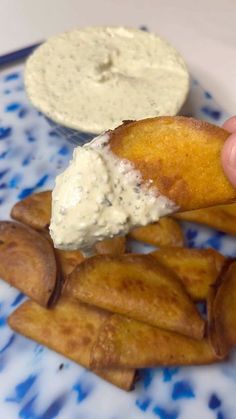 a person dipping something into some kind of sauce on top of french fries with dip