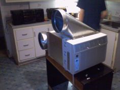 a man standing in a kitchen next to an old fashioned projector on top of a table