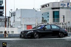 a black car parked in front of a building on the side of a road with buildings behind it