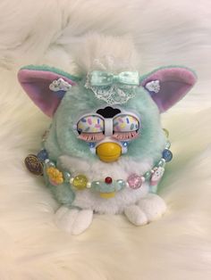 a stuffed animal wearing a tiara on top of a white fur covered floor with beads