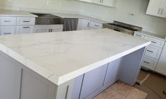 a large kitchen with white cabinets and marble counter tops in the process of remodeling