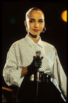 a woman holding a microphone in her right hand and wearing black gloves on the other