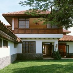 a white house with brown tiled roof and green grass in the front yard, on a sunny day