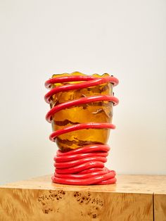 there is a glass vase with red cords in it on top of a wooden table