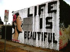 a brick wall with graffiti on it and the words life is beautiful painted on it