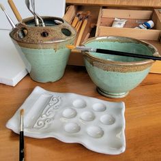 two bowls with spoons in them sitting on a table next to an empty tray