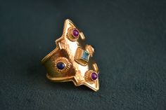 This medieval ring is inspired by old byzantine and etruscan jewelry. Made with solid 18K Gold (750 Gold), this rings offers not only a great shape, but also 5 gemstones. It has on it 2 round rubies, 2 round sapphires and one square princess cut emerald in the middle. Total Gemstone Weight: 1.00 CT Byzantine Style Gemstone Rings For Ceremonial Occasion, Byzantine Gemstone Rings For Ceremonial Occasions, Byzantine Yellow Gold Rings With Gemstone, Gold Byzantine Style Ruby Ring, Handmade Byzantine Gold Rings, Gold Byzantine Ruby Ring With Gemstone, Byzantine Style Ceremonial Gemstone Rings, Handmade Medieval Gold Rings, Ceremonial Byzantine Rings With Historical Design