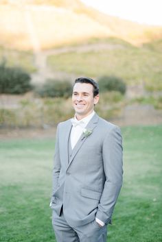 a man in a gray suit standing on top of a lush green field