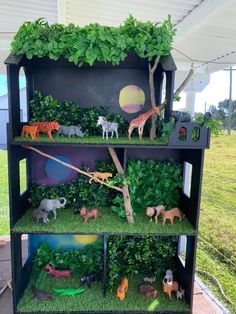 a shelf filled with lots of fake animals on top of green grass and plants in front of a white roof