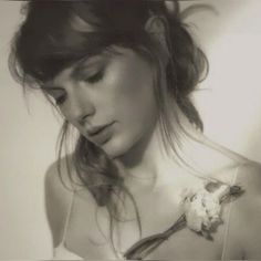 a black and white photo of a woman with flowers in her hair holding a cell phone