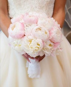 a bridal holding a bouquet of white and pink peonies in her hand