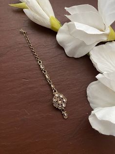 a close up of a flower on a table with a chain attached to it and flowers in the background