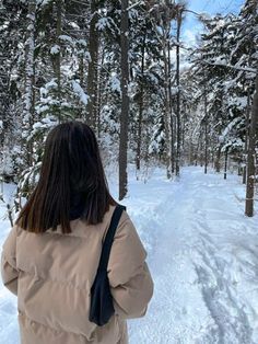 a woman is walking through the woods in winter