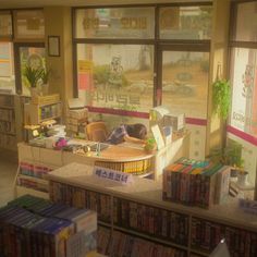 a room filled with lots of books next to a window covered in signs and posters