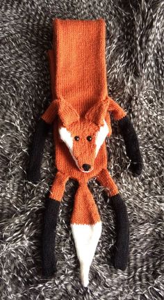 an orange knitted animal laying on top of a blanket