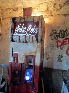 an old fashioned soda machine with graffiti on the wall behind it and a neon light in front of it