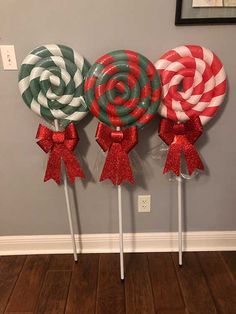 three lollipops with bows on them are sitting in front of a wall