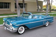 an old blue car parked in front of a building