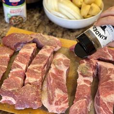 someone is pouring seasoning on some raw meat