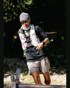 a man is running in the park with his hat on and sunglasses on while wearing shorts