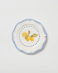 a plate with two lemons painted on the front and side, sitting on a white surface