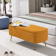 an orange ottoman sits in front of a bed