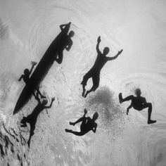 four people are swimming in the water with their surfboards