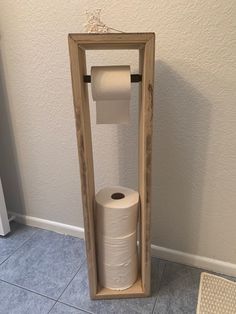 a toilet paper dispenser made out of an old wooden frame with two rolls of toilet paper in it