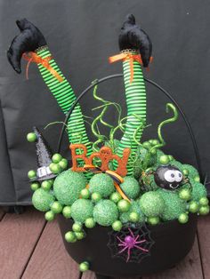 a black pot filled with green balls and halloween decorations on top of a wooden floor