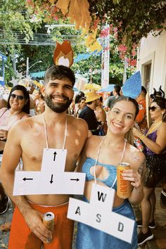 a man and woman dressed up in swimsuits holding beer signs at an outdoor event