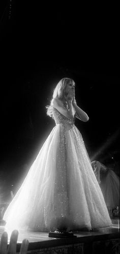 black and white photograph of a woman in a gown on stage with her hands behind her head