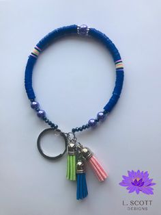 a blue beaded bracelet with two tassels and a keychain hanging from it