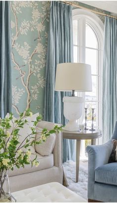 a living room filled with furniture and a lamp on top of a table next to a window