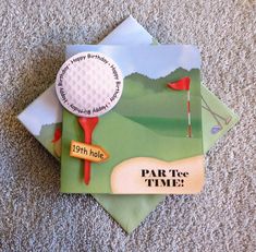 a birthday card with a golf ball and tee on it sitting on top of two envelopes