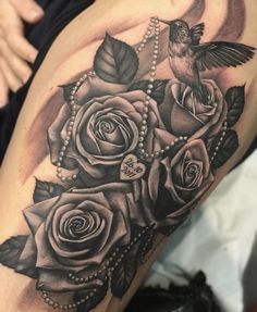 a woman's thigh with roses, pearls and a hummingbird on the side